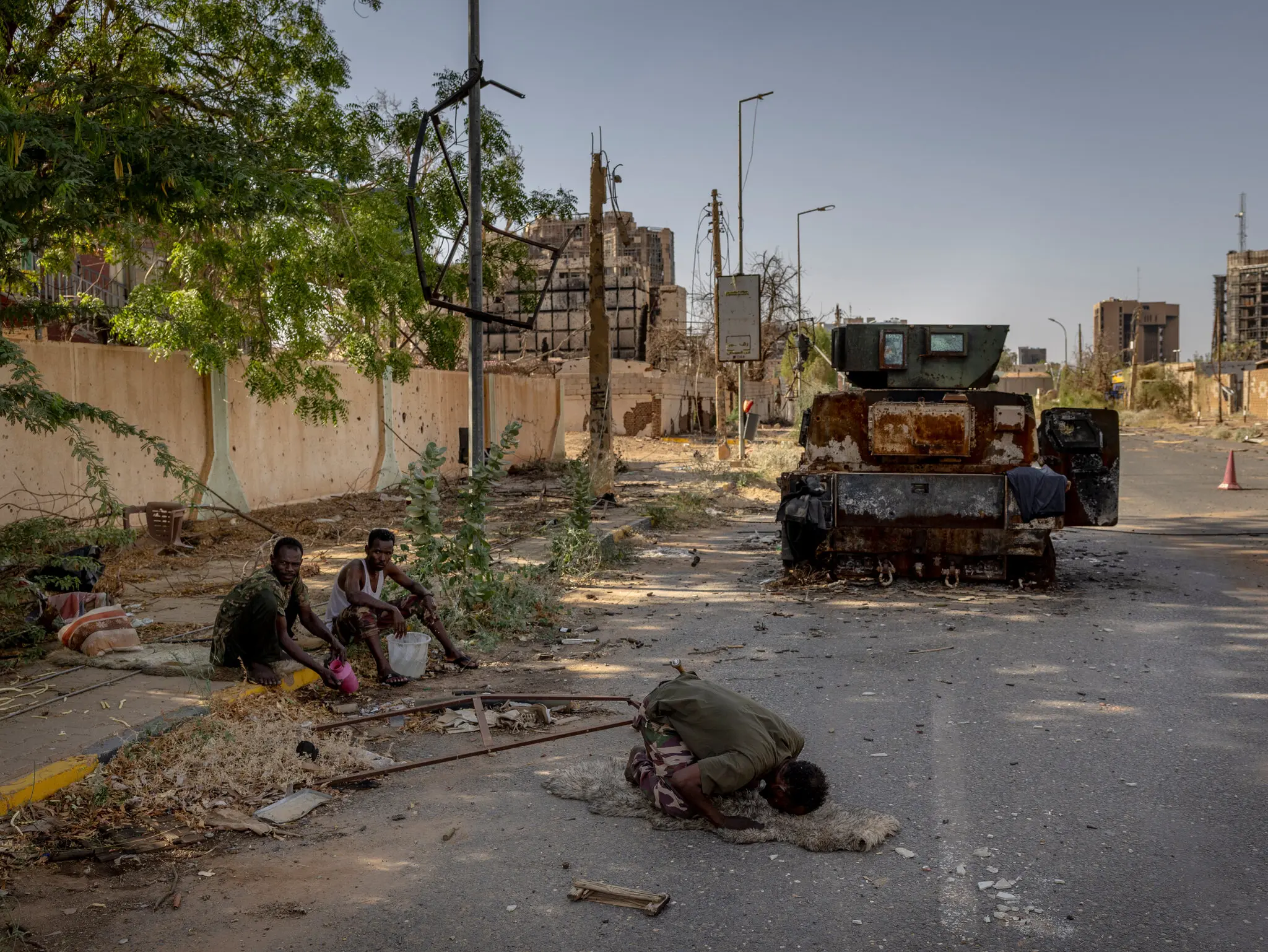 На завалених уламками вулицях у центрі Хартума суданський солдат молився перед згорілою бронетехнікою